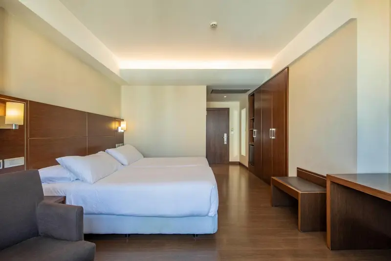 Une chambre lumineuse avec un grand lit et un bureau.
