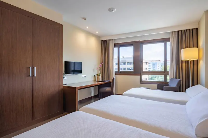 Une chambre d'hôtel lumineuse avec un bureau près de la fenêtre.