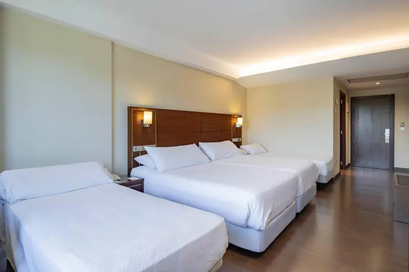 Une chambre lumineuse avec deux lits doubles et une table de chevet.