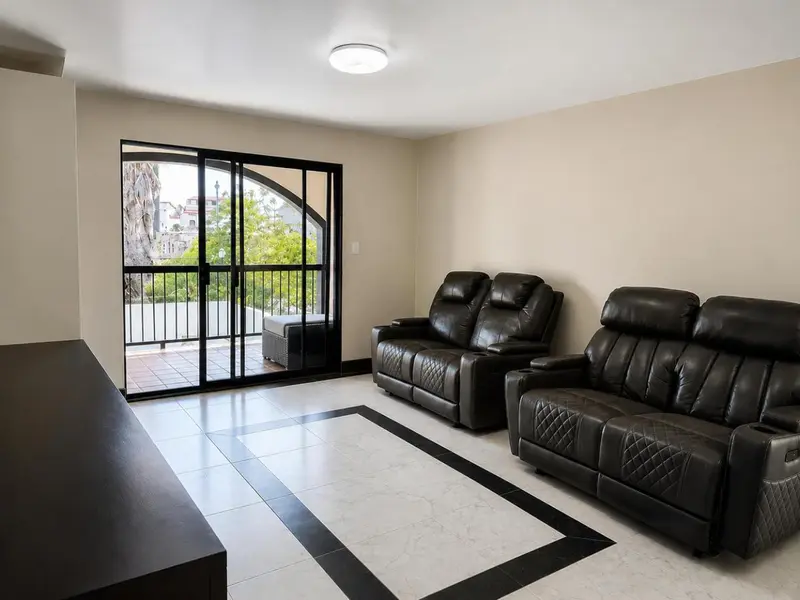 Espace de détente intérieur avec canapés en cuir et accès à une terrasse.