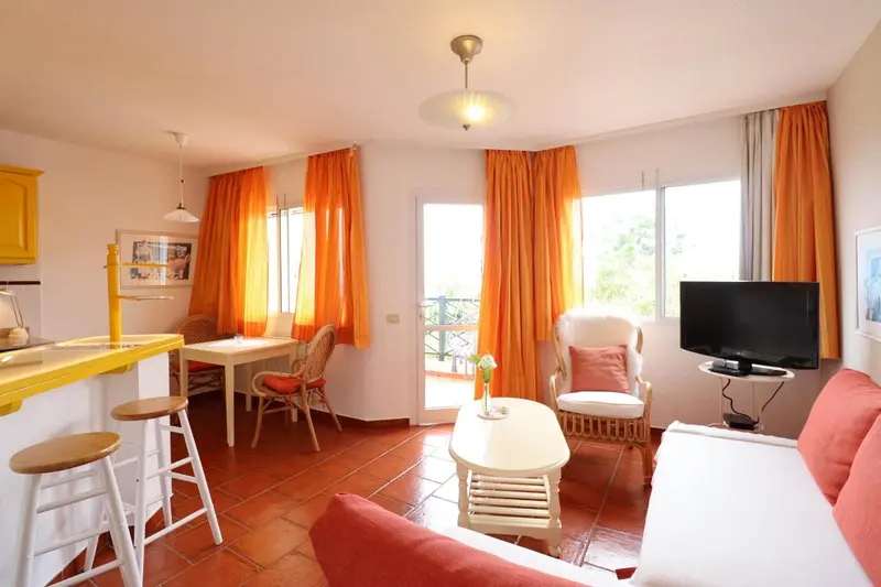 Espace de vie lumineux avec coin repas et canapé rouge.