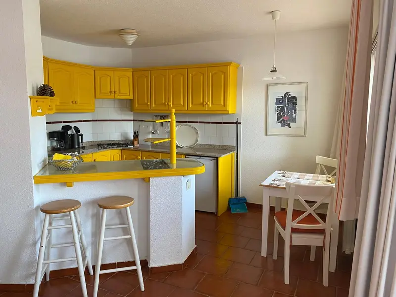 Une cuisine jaune vif avec un comptoir bar et une table à manger.
