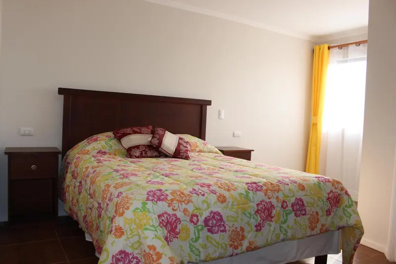 Une chambre lumineuse avec un grand lit recouvert d'une courtepointe fleurie.