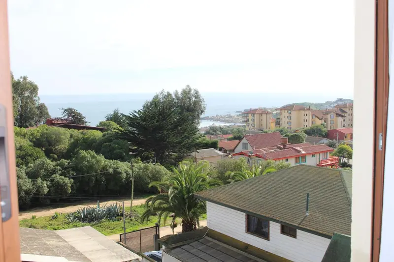 Vue d'ensemble sur une ville côtière verdoyante depuis une fenêtre.