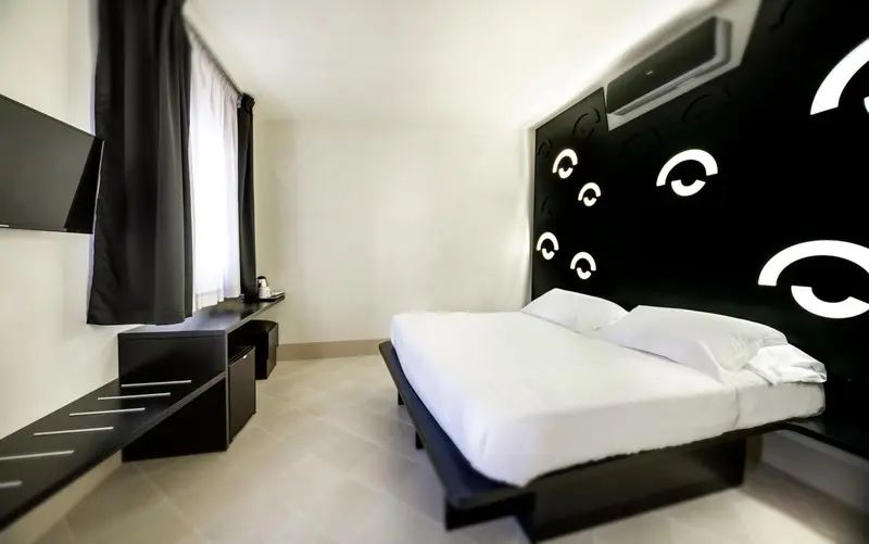 Une chambre moderne avec un lit blanc et un mur décoré de motifs graphiques.