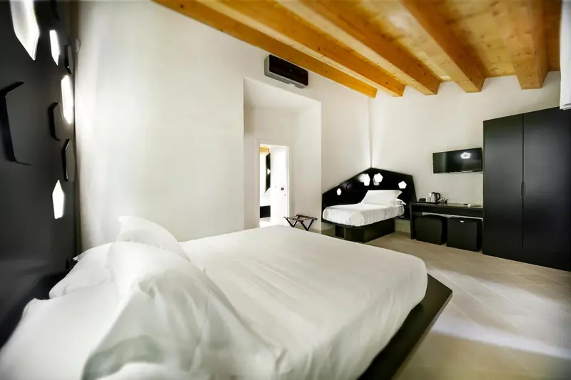 Une chambre lumineuse avec un lit blanc et un mobilier sombre.