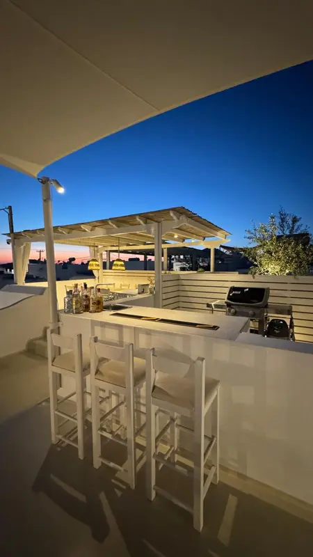 Un bar en plein air avec des tabourets et une vue sur la mer au coucher du soleil.