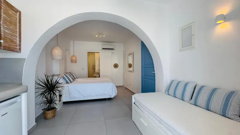 Une chambre lumineuse avec un lit et un coin salon.