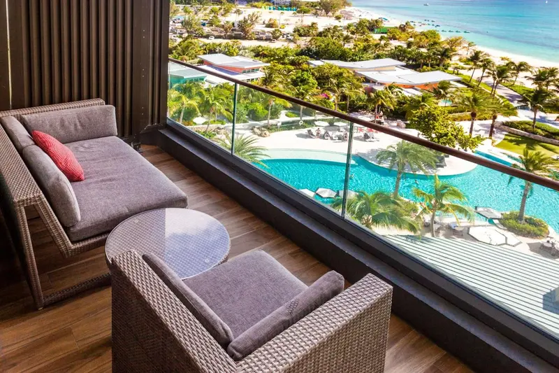 Espace de détente extérieur avec mobilier confortable et vue sur une piscine et la mer.