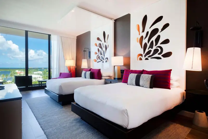 Chambre moderne avec deux lits et vue sur la mer.