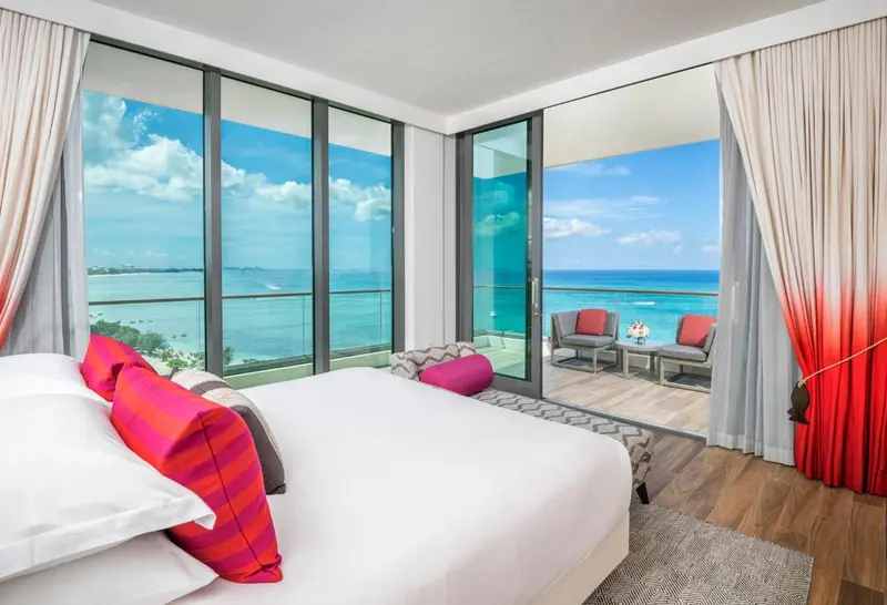 Une chambre lumineuse avec un grand lit donnant sur une terrasse et la mer.