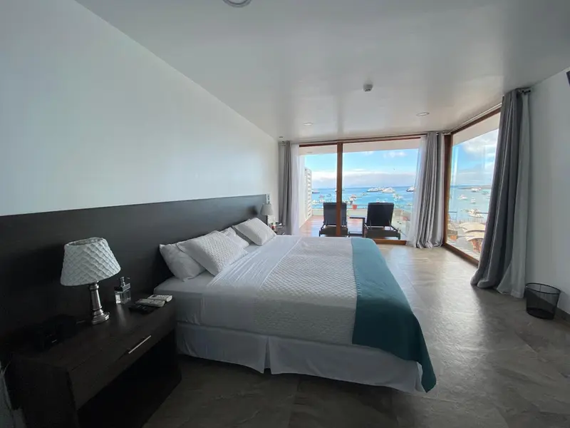 Une chambre lumineuse avec un grand lit donnant sur une vue mer.