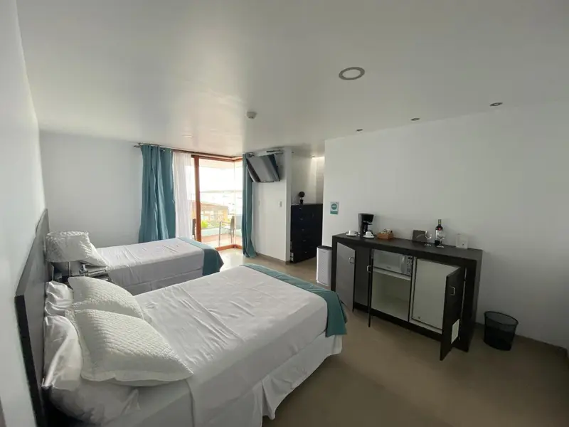 Chambre lumineuse avec deux lits simples et un bureau noir.