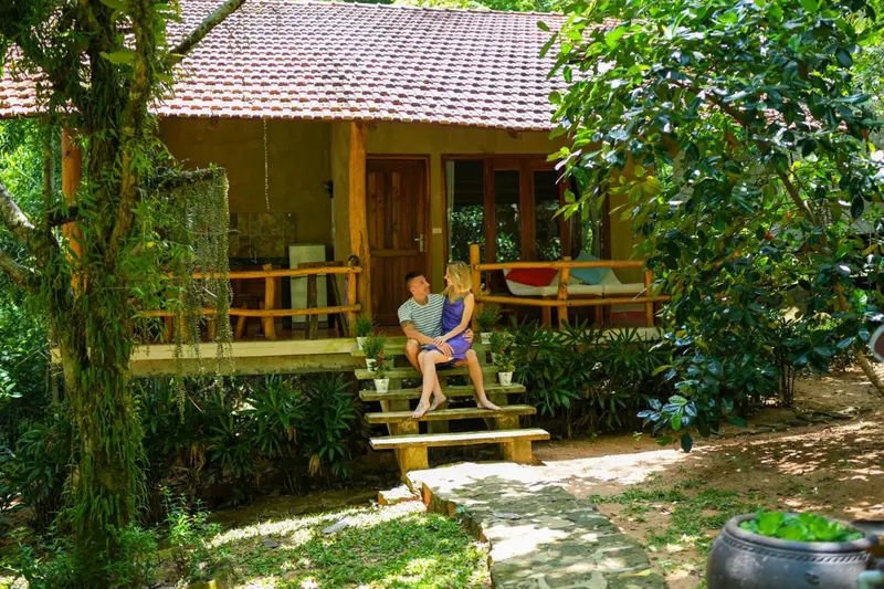 Un couple est assis sur les marches d'un bungalow avec une terrasse.