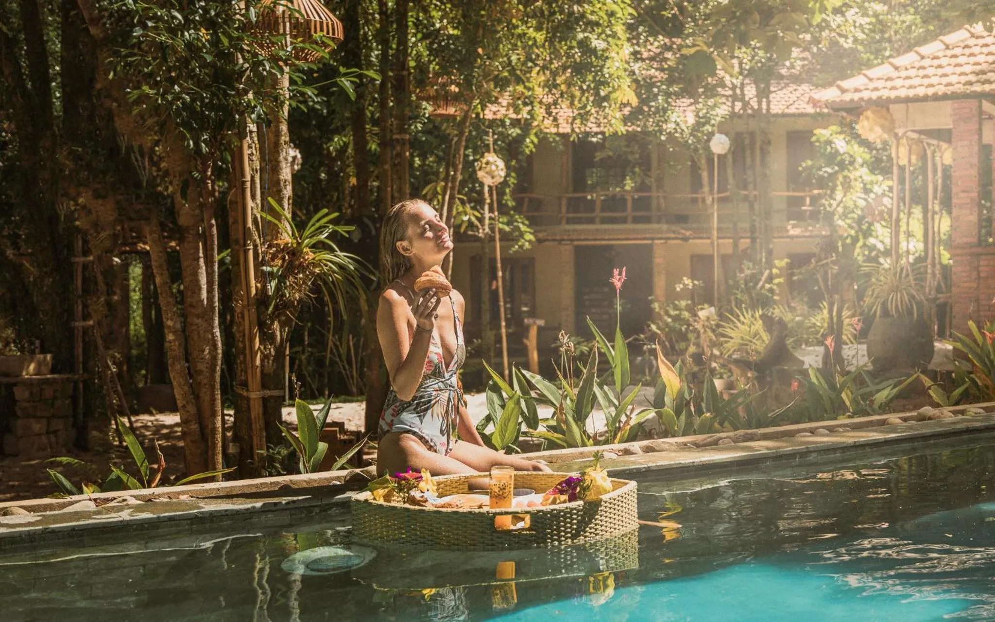 Une femme se détend dans une piscine avec un plateau de nourriture et de boissons.