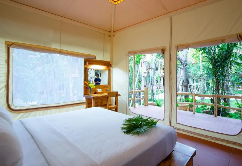Une chambre lumineuse avec un lit recouvert de blanc et une vue sur la végétation.
