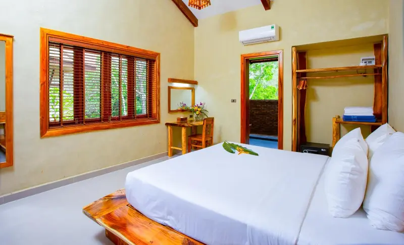 Une chambre lumineuse avec un lit recouvert de blanc et une décoration en bois.