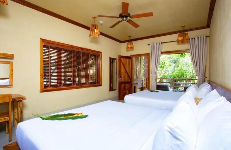 Une chambre lumineuse avec deux lits simples et un accès à une terrasse.