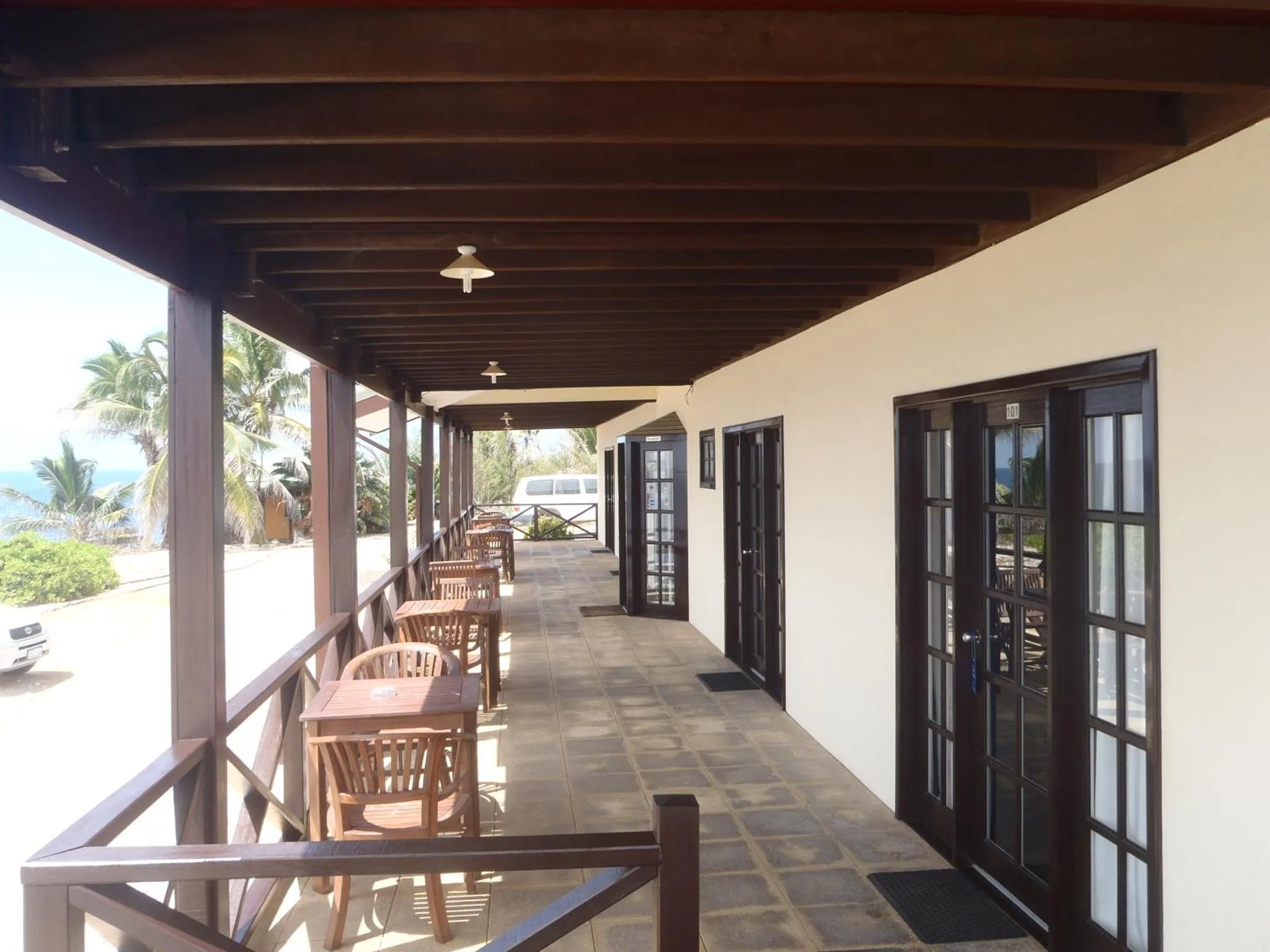 Terrasse couverte avec tables et chaises donnant sur la mer.