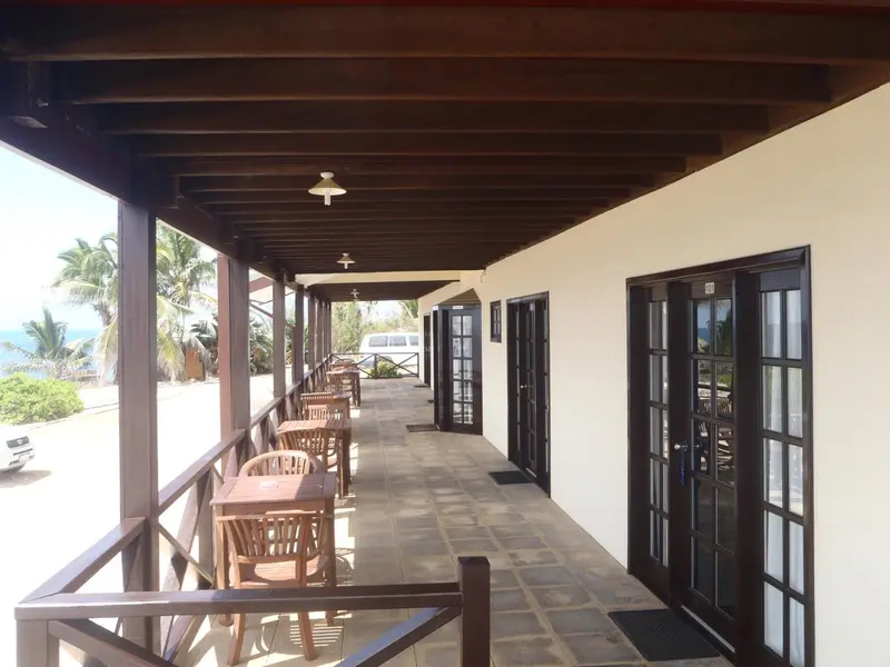 Terrasse couverte avec tables et chaises donnant sur la mer.
