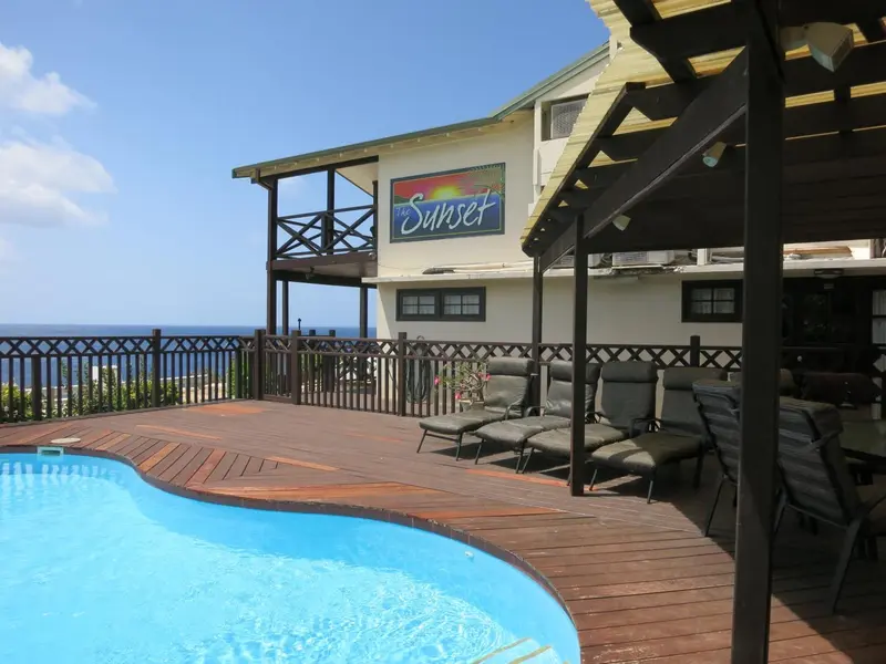 Terrasse en bois avec chaises longues et piscine au premier plan.