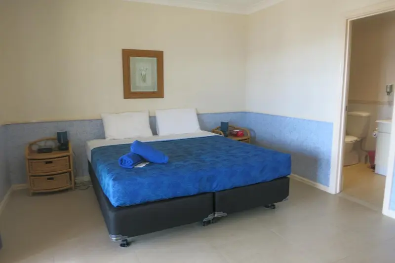 Une chambre lumineuse avec un grand lit recouvert d'une couverture bleue.
