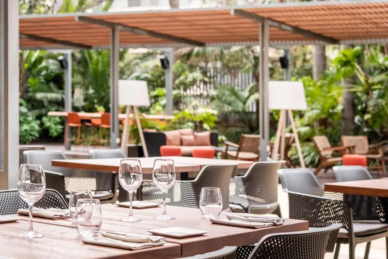 Une terrasse ombragée avec des tables et des chaises pour les repas.