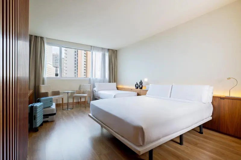 Chambre lumineuse avec lits jumeaux et mobilier moderne.