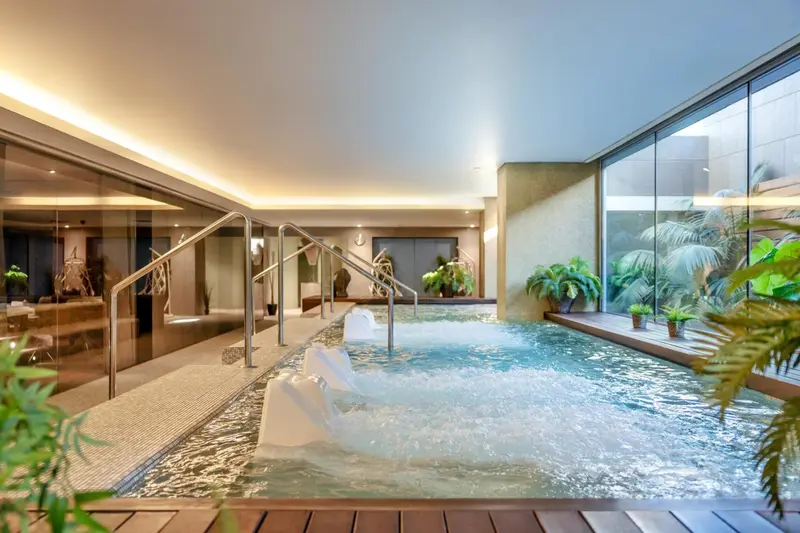 Une piscine intérieure avec des jets de massage et une végétation luxuriante.