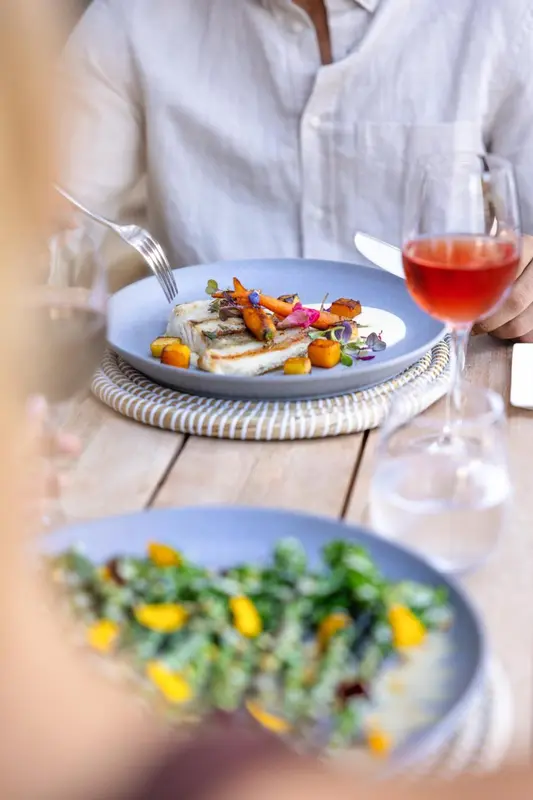 Une assiette de poisson est servie avec une salade et une boisson.