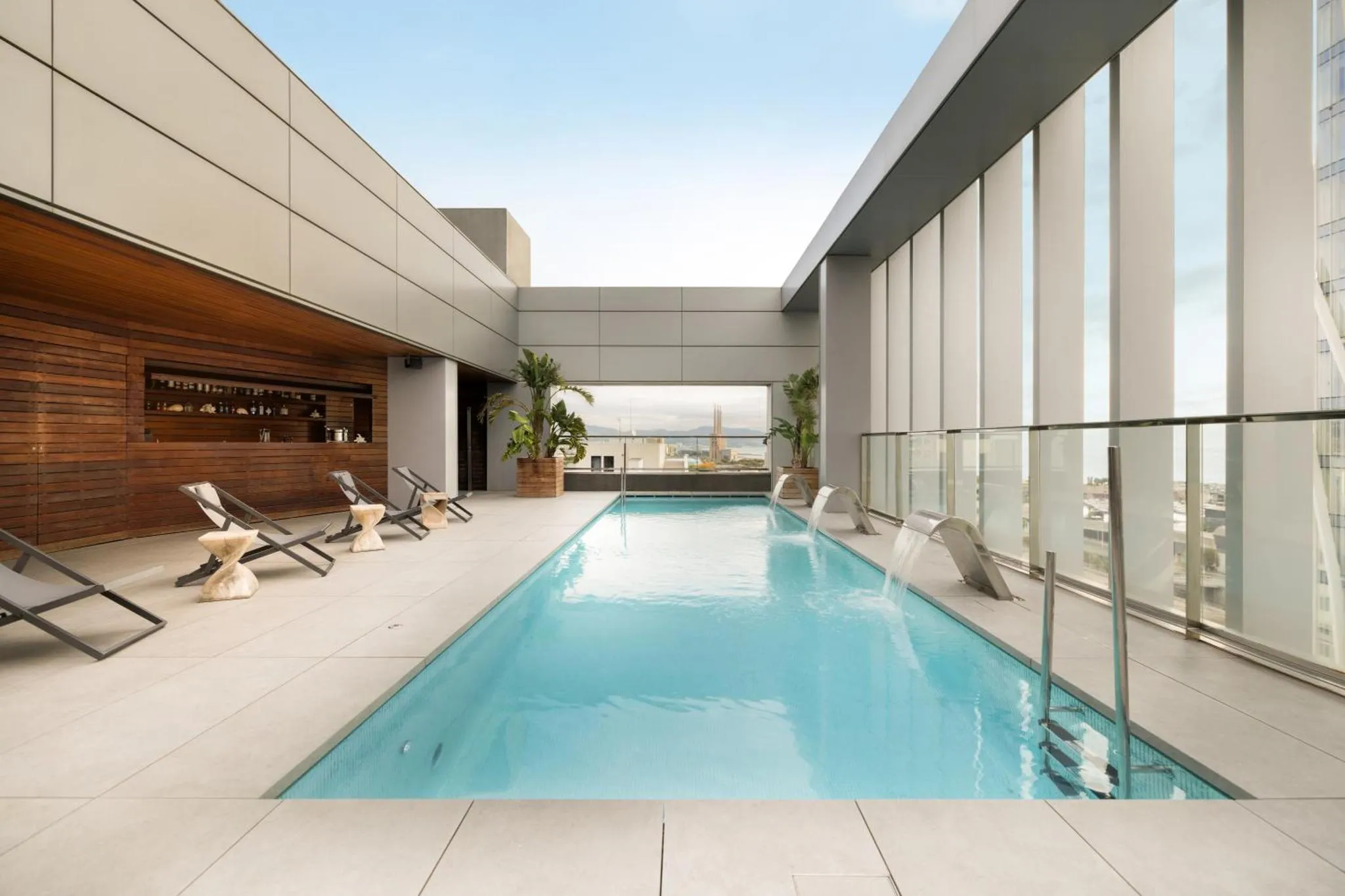 Une piscine rectangulaire avec des transats et une vue sur la ville.