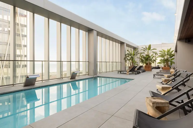 Une piscine rectangulaire intérieure avec des transats alignés le long d'une baie vitrée.