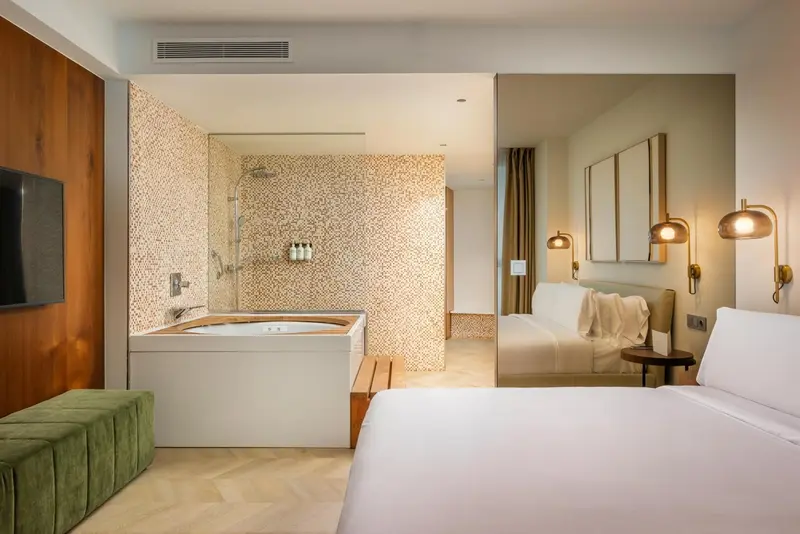 Une chambre lumineuse avec un lit et une salle de bain attenante.
