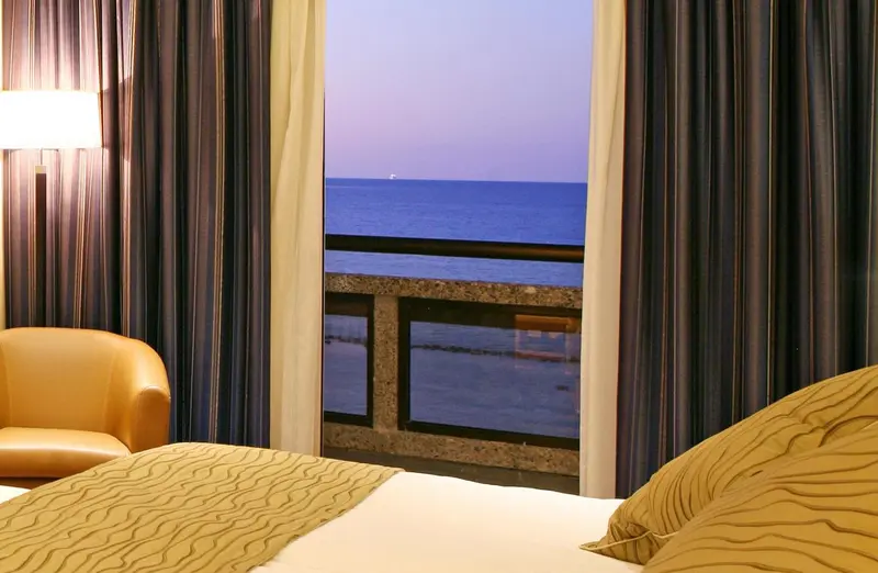Une chambre d'hôtel avec vue sur la mer depuis un balcon.