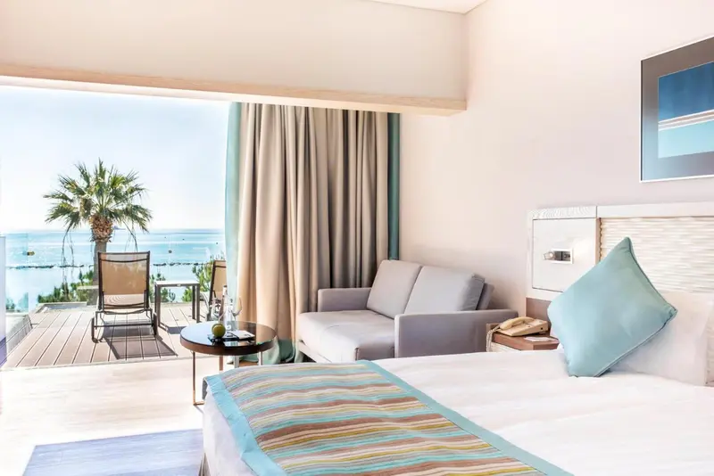 Une chambre lumineuse s'ouvre sur une terrasse avec vue sur la mer.