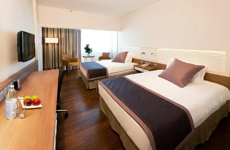 Une chambre d'hôtel lumineuse avec deux lits simples et un bureau.