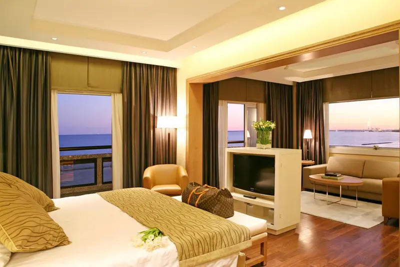Une chambre lumineuse avec un grand lit et un espace salon donnant sur la mer.