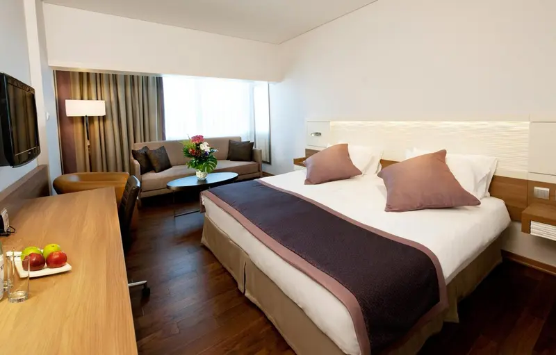 Une chambre lumineuse avec un coin salon et un lit double.