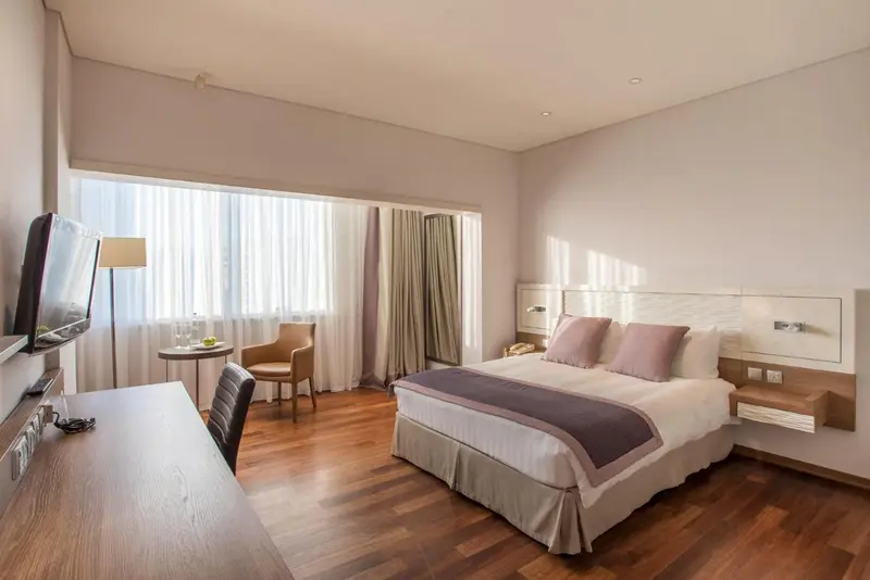 Une chambre d'hôtel lumineuse avec un lit double et un coin salon.