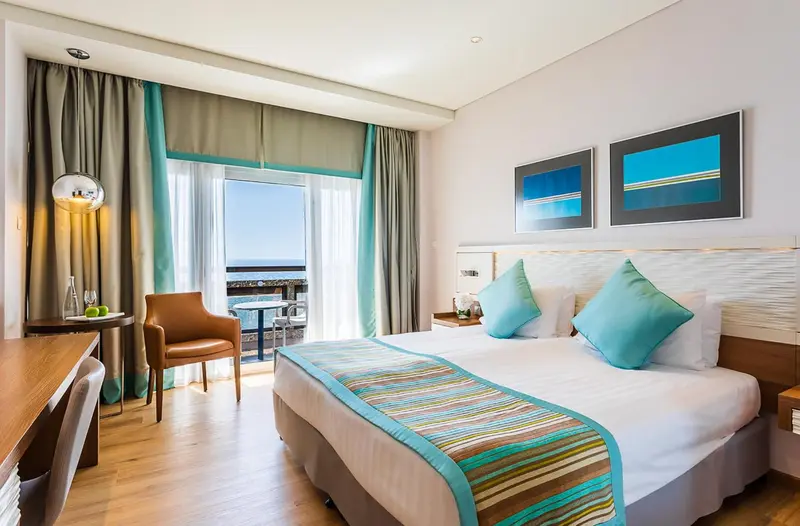 Chambre lumineuse avec un lit confortable et une vue sur la mer.