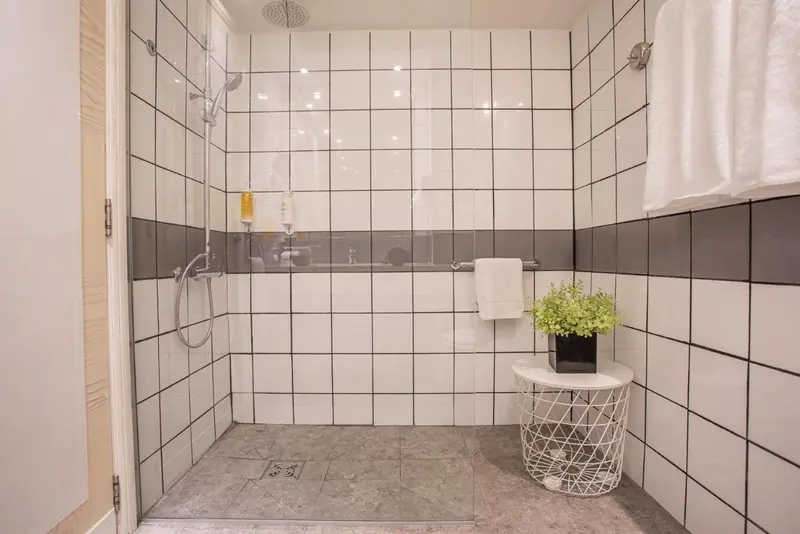 Une douche à l'italienne moderne avec des carreaux blancs et gris.