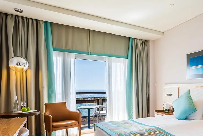 Une chambre lumineuse avec un fauteuil et une vue sur la mer.