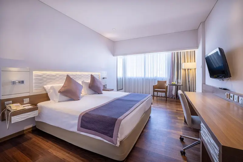 Une chambre d'hôtel lumineuse avec un grand lit et un bureau.