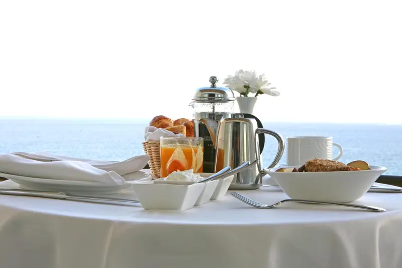 Un petit-déjeuner est servi sur une table blanche avec vue sur la mer.