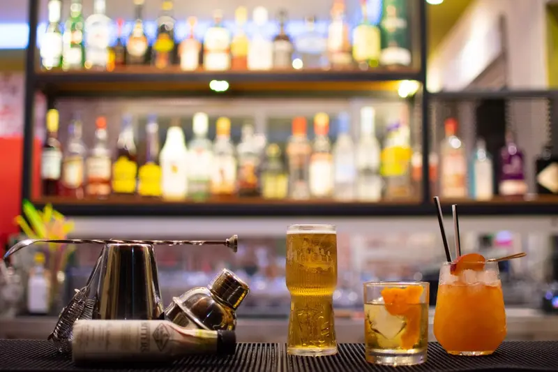 Un comptoir de bar présente des boissons colorées et des outils de mixologie.