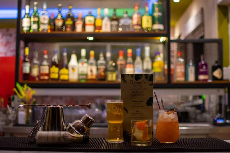 Un comptoir de bar présente des bouteilles d'alcool et des cocktails colorés.