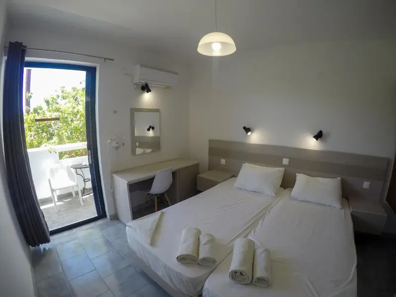 Chambre lumineuse avec un lit double et un accès à une terrasse.