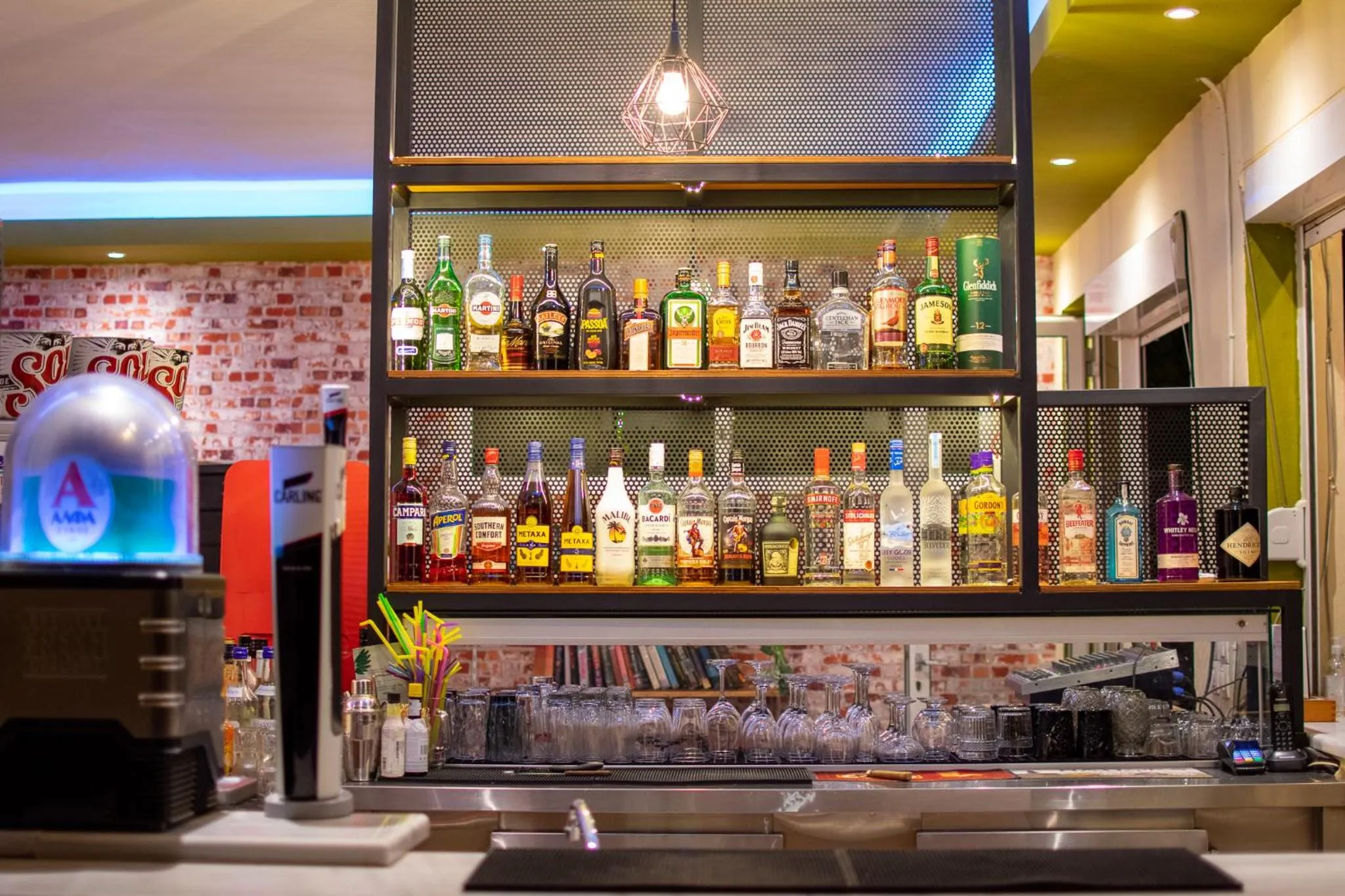 Un comptoir de bar présente une variété de bouteilles d'alcool éclairées.