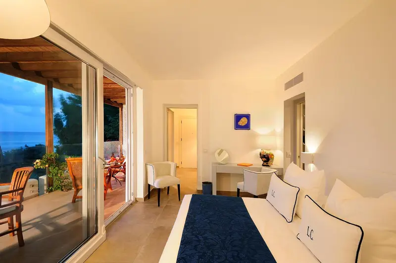 Une chambre lumineuse s'ouvre sur une terrasse avec vue sur la mer.