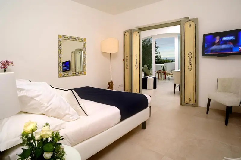 Une chambre lumineuse avec un lit recouvert d'une courtepointe foncée et un miroir décoratif.